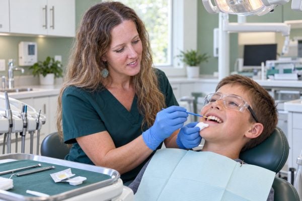 Hygienist Kara applying fluoride varnish to a child's teeth